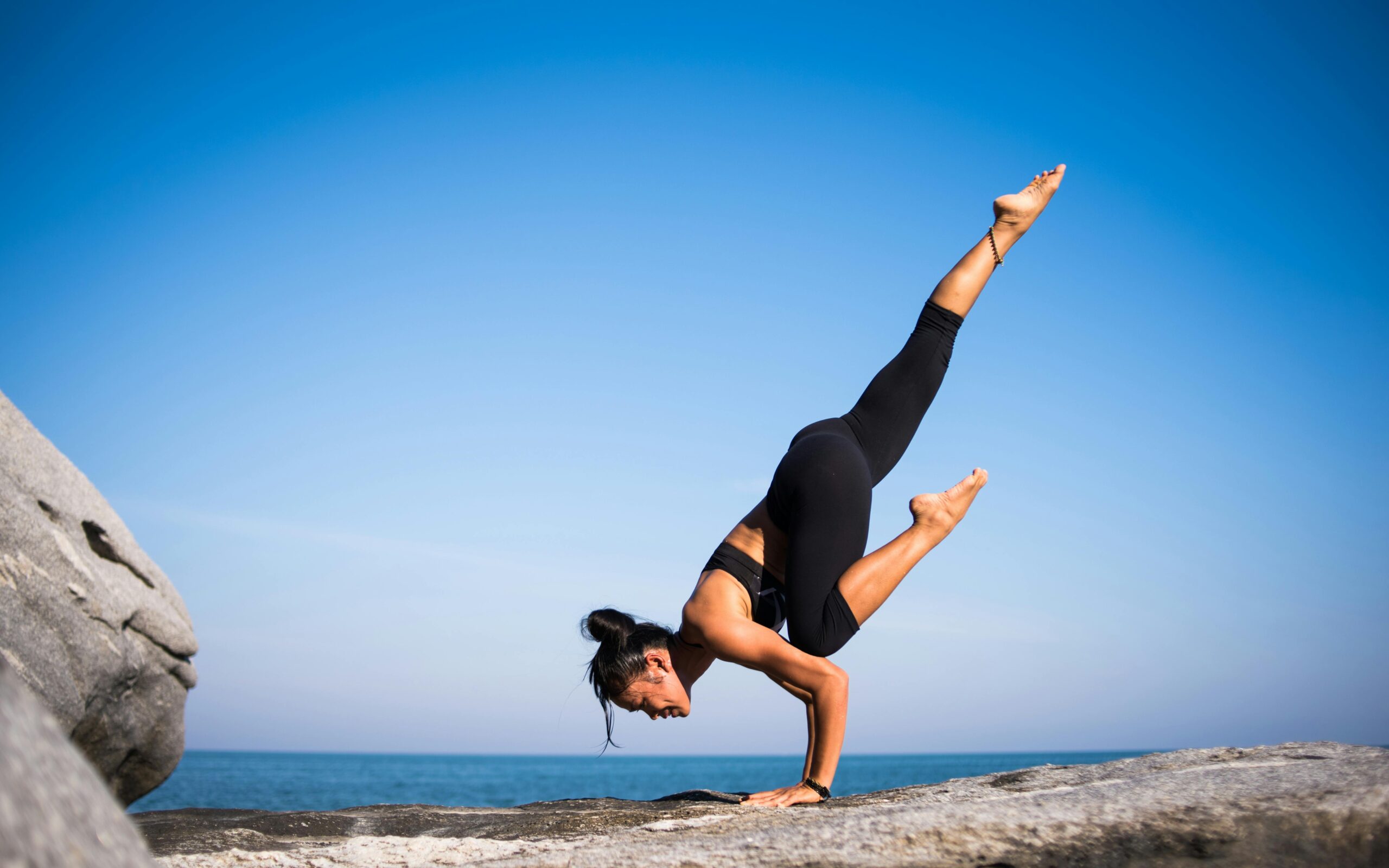 Frau macht Yoga auf einem Felden am Meer