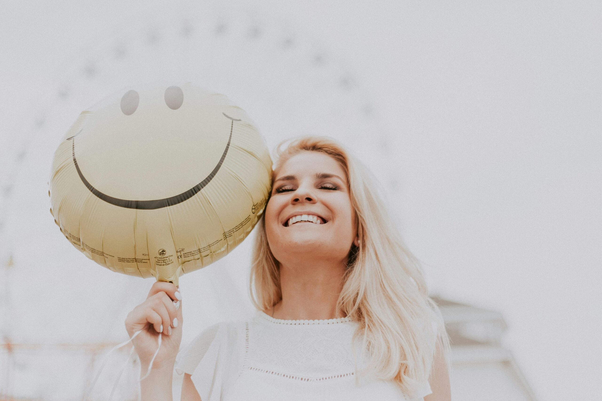 Frau lacht mit Smiley Luftballon